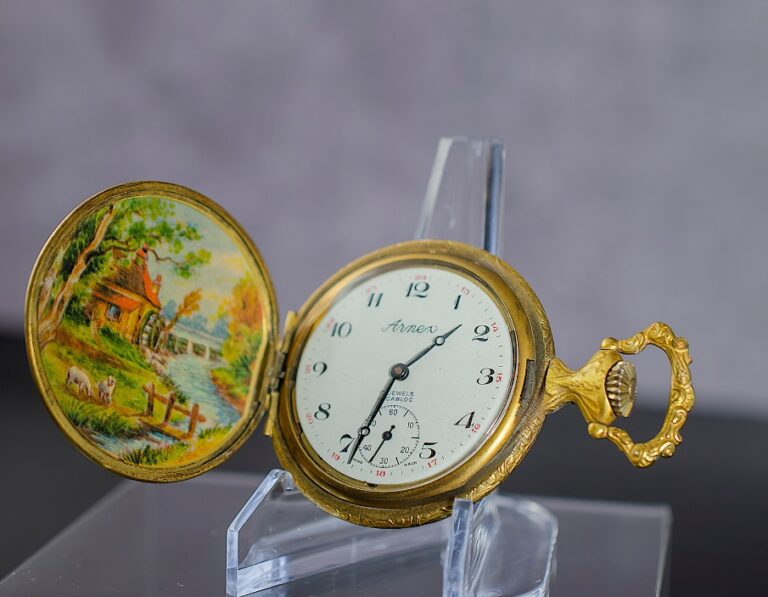 A gold pocket watch on a stand Description automatically generated