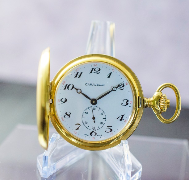 A gold pocket watch on a stand Description automatically generated