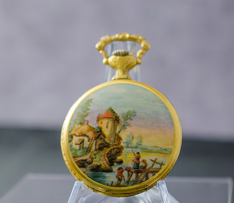 A pocket watch on a stand Description automatically generated