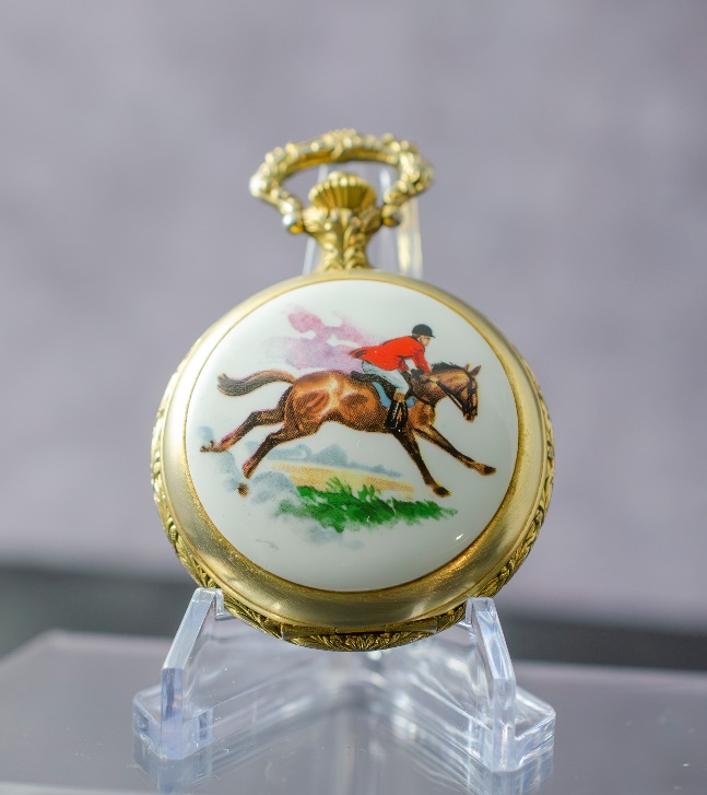 A pocket watch with a picture of a horse Description automatically generated